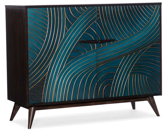 A dark wood cabinet with two doors featuring an intricate teal and gold geometric swirling pattern. The cabinet has mid-century modern tapered legs and sleek handles.