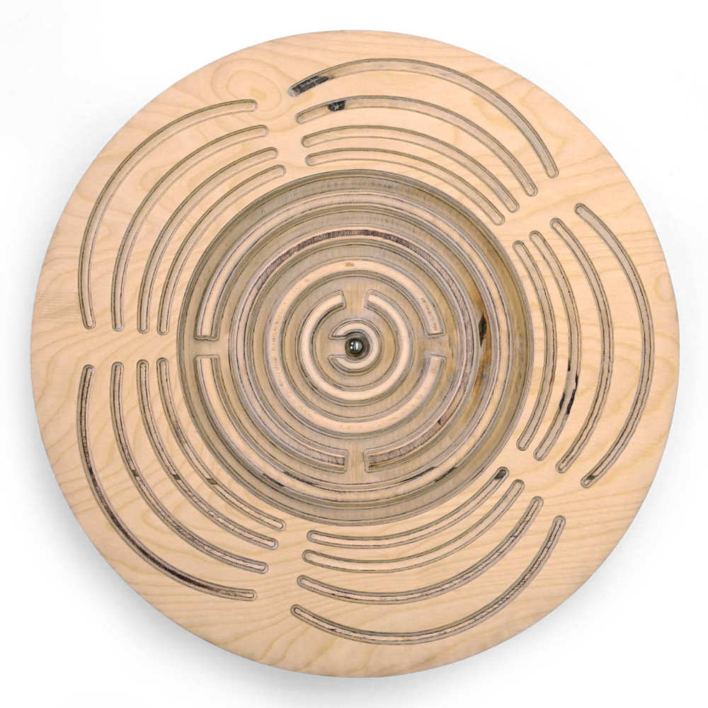 Introducing the Circular Labyrinth Balance Board by Tooba Furniture Factory: a meticulously crafted round wooden game featuring concentric paths and intricate passages carved into its surface. It includes a small metal ball that players must navigate through the maze by tilting and maneuvering, much like a delicate balance board.