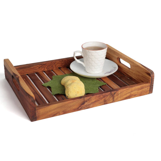 The Straight Strip Tray by Tooba Furniture Factory is a handcrafted wooden tray with a slatted bottom, featuring a white teacup and saucer with a red rim filled with tea, a green napkin, and two shortbread cookies. The serving tray has side handles and sits on a white surface, adding a touch of elegance to your kitchen decor.