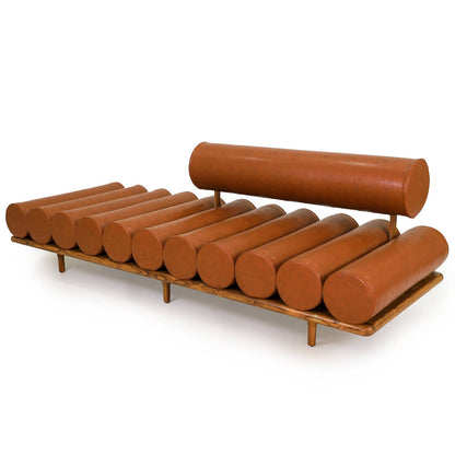 The Cylinder Cushion Sofa by Tooba Furniture Factory is a modern, minimalist piece with a distinct design featuring multiple cylindrical cushions arranged horizontally on a wooden frame. The cushions are upholstered in brown leather, and the backrest is made from a single, long cylindrical cushion.