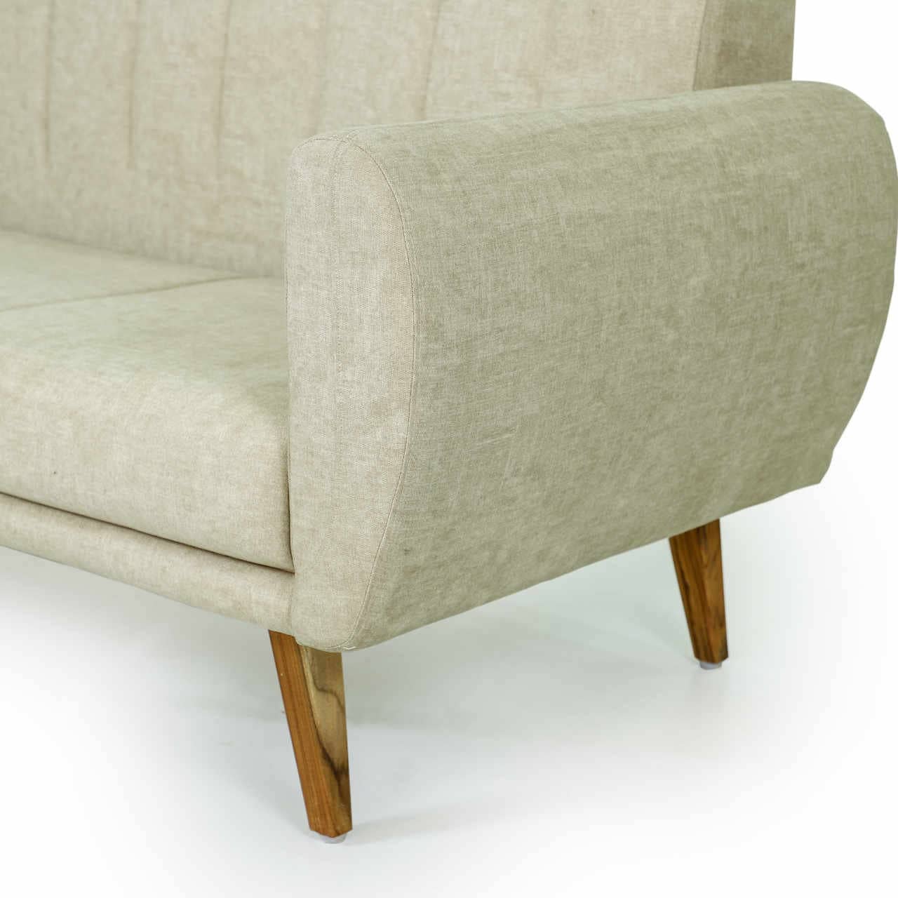 Tooba Furniture Factory presents the Arm sofa: a beige, mid-century modern piece with wooden legs and vertical stitching on the backrest. This minimalist design provides seating for up to three people, featuring slightly curved armrests and angled outward legs.