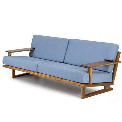 The Spoke Wooden Sofa by Tooba Furniture Factory is a modern mid-century style wooden piece with a minimalist design. It features light-blue fabric cushions and angled armrests, complemented by a sleek wooden frame with a natural finish. This exquisite sofa comfortably seats three and has a slightly reclined backrest for added comfort.